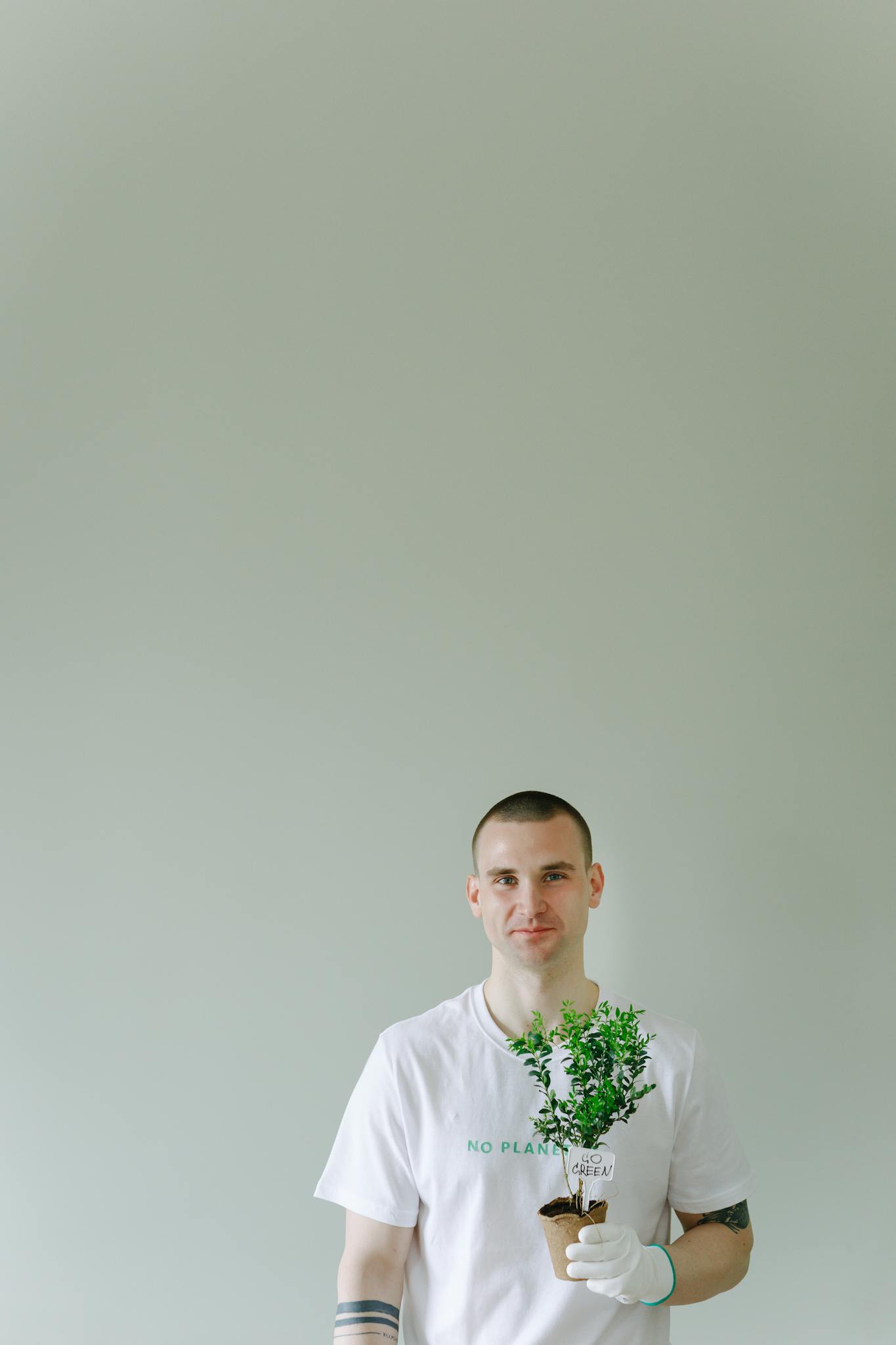 Smiling young man holding a potted plant symbolizing eco-friendly living.